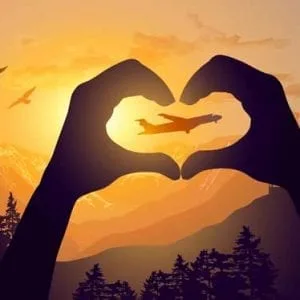a silhouette of hands making a heart with a plane in the background