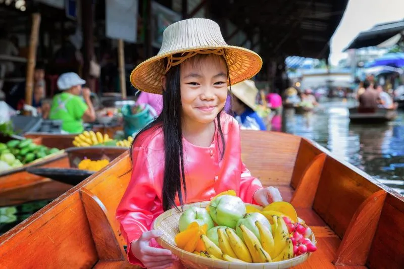 a child in a boat with a basket of fruit