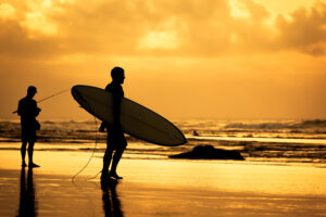 silhouette of a surfer walking to the ocean during sunset