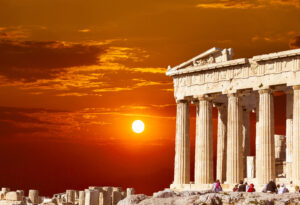 Parthenon temple on the Athenian Acropolis, Greece, with the sun setting in the background creating a red sky